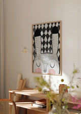 Quadro emoldurado com coelho branco de olhos fechados, bochechas rosadas, fundo de losangos pretos e brancos e estilo infantil moderno para quarto de bebé ou de criança. Disponível em kudeko.com