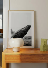 Wandbild mit einem Wal, der aus dem Meer auftaucht, in Weiß, Schwarz und Grau, mit kontrastreicher Meereskomposition und fotografischem Stil. Erhältlich auf kudeko.com
