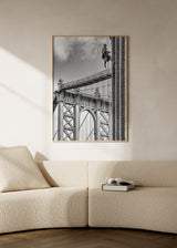 Quadro da Ponte de Manhattan a preto e branco com trabalhador suspenso junto a edifício de tijolo, composição urbana de estilo fotográfico em tons cinzentos, pretos e brancos, com referência nova-iorquina. Disponível em kudeko.com