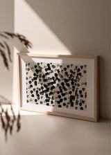 Tableau horizontal avec petites formes abstraites noires et grises dispersées sur fond blanc cassé, composition organique au style contemporain en noir et blanc. Disponible sur kudeko.com