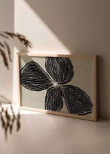 Quadro horizontal com grande flor preta de três pétalas sobre fundo bege, linhas orgânicas marcadas, contraste suave e composição floral contemporânea de estilo depurado. Disponível em kudeko.com