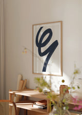 Tableau encadré avec grande forme abstraite au trait courbe bleu marine sur fond blanc cassé, composition fluide au style contemporain et raffiné. Disponible sur kudeko.com