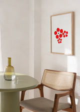 Gerahmtes Wandbild mit roten Blumen in runden Formen, weißem Hintergrund, kleinen schwarzen Zentren und modernem minimalistischem Stil, klar und elegant gestaltet. Erhältlich auf kudeko.com
