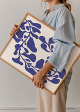 Quadro com composição botânica abstrata de folhas e caules azuis sobre fundo branco quebrado, com formas orgânicas fluidas e estilo moderno depurado. Disponível em kudeko.com