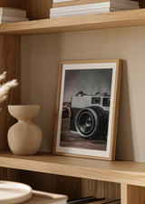 Tableau avec appareil photo rétro au premier plan sur surface en bois, tons gris, noirs et bruns, style vintage élégant et nostalgique. Disponible sur kudeko.com