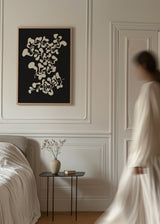 Quadro botânico emoldurado com folhas branco marfim, caules finos curvos, formas orgânicas sobre fundo preto e estilo minimalista contemporâneo. Disponível em kudeko.com