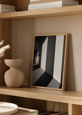 Quadro de arquitetura a preto e branco com grandes muros, luz marcada, sombras alongadas, pequena figura humana e estilo fotográfico contemporâneo. Disponível em kudeko.com