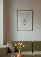 Quadro emoldurado com ramo botânico e folhas em tons de cobre, camel e castanho suave sobre fundo bege claro, de estilo minimalista e natural. Disponível em kudeko.com