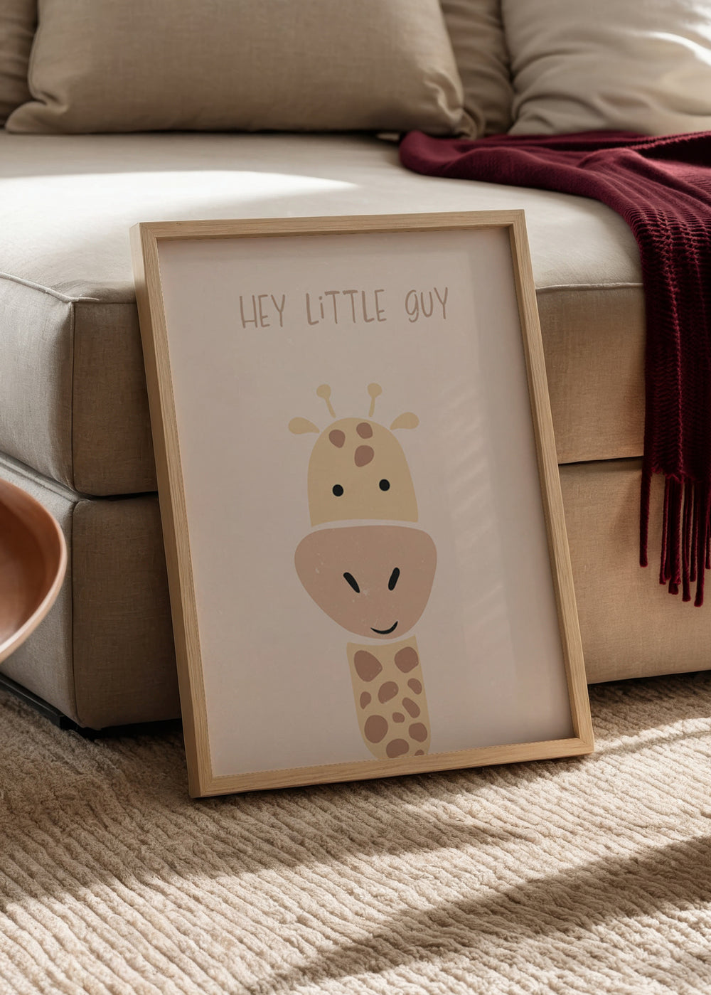 Gerahmtes Wandbild mit lächelnder Giraffe in schlichten Formen, hellrosa Hintergrund, Beige, Creme und sanftem Braun, mit Schriftzug Hey Little Guy im kindlichen Stil. Erhältlich auf kudeko.com