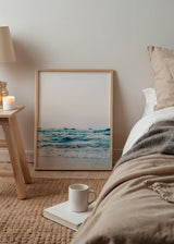 Gerahmtes Wandbild mit ruhigem Meer, sanften Wellen am Ufer, hellem Sand, lichtdurchflutetem Himmel sowie Türkisblau, Weiß und Beige in fotografischem Stil. Erhältlich auf kudeko.com