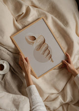 Tableau encadré avec caracola marine spiralée en beige, sable et brun doux sur fond neutre, avec composition minimaliste et cercle estompé. Disponible sur kudeko.com