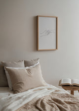 Quadro emoldurado com duas mãos quase a tocar-se, linhas pretas finas sobre fundo bege claro, composição limpa e estilo minimalista contemporâneo. Disponível em kudeko.com
