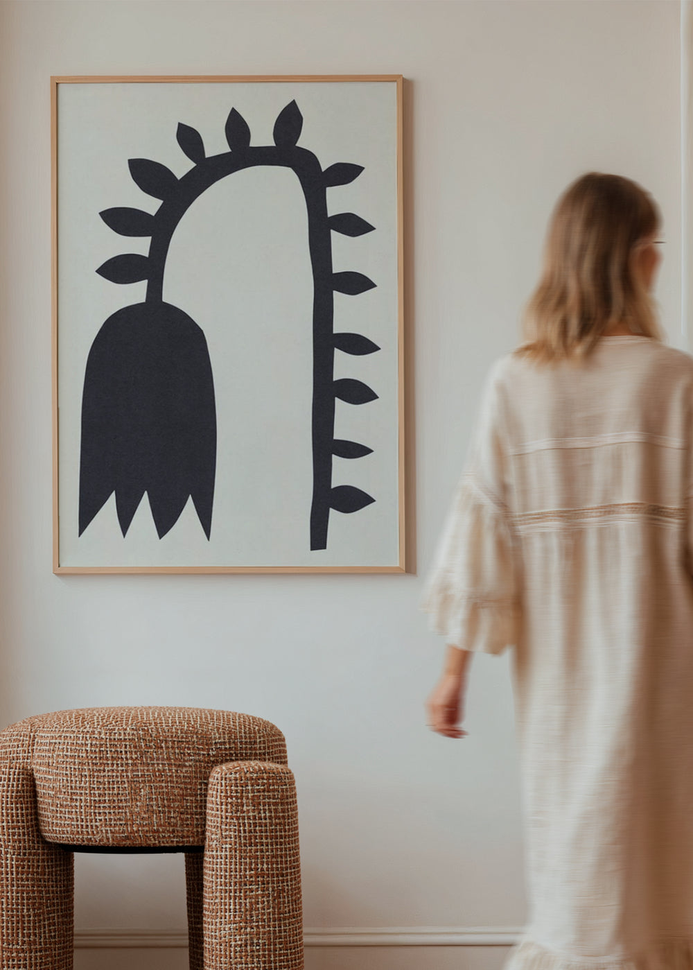 Wandbild mit schwarzer Blüte in länglicher Silhouette, geschwungenem Stiel, seitlichen Blättern, warmweißem Hintergrund und minimalistischer Komposition mit klaren Linien. Erhältlich auf kudeko.com