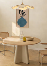 Tableau encadré avec vase bleu arrondi, branches aux feuilles noires, fond beige doux et composition minimaliste aux lignes épurées. Disponible sur kudeko.com