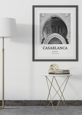 Cuadro con arco monumental de arquitectura marroquí, relieves ornamentales, mosaicos geométricos y tonos blanco, gris y negro, de estilo fotográfico. Disponible en kudeko.com