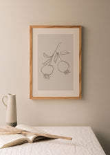 Cuadro de dos granadas colgando de una rama con hojas, en tonos gris topo sobre fondo claro, de estilo minimalista. Disponible en kudeko.com