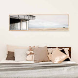 cuadro horizontal encima de la cama y fotográfico de playa con caseta y dos personas mirando el horizonte - kudeko