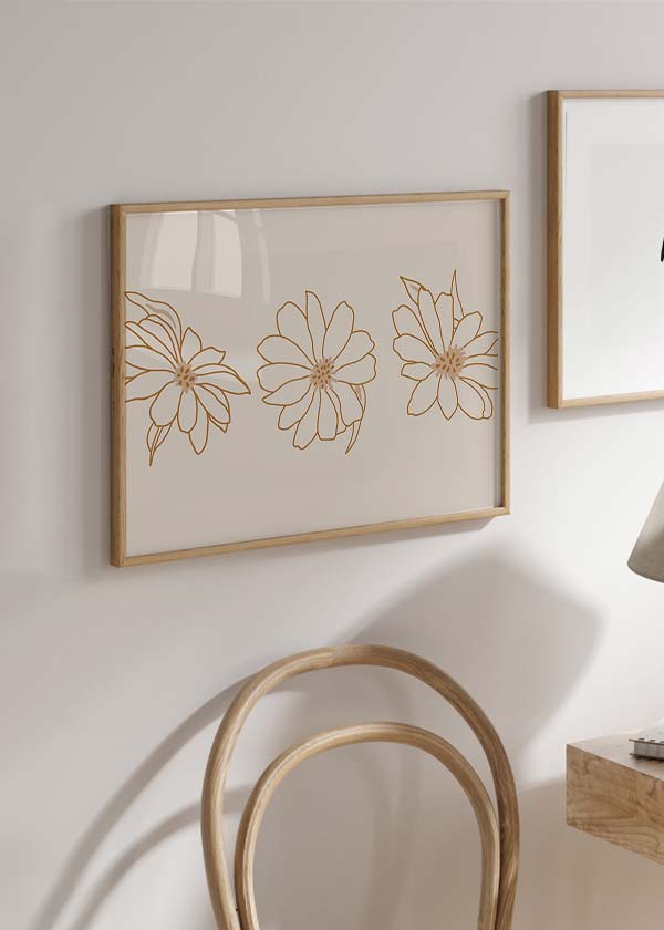 Gerahmtes Wandbild mit drei fein gezeichneten Blumen in sanftem Braun auf hellem Beigefond, leichte Komposition im floralen Illustrationsstil, natürlich und ausgewogen. Erhältlich auf kudeko.com