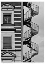 Wandbild mit urbaner Fassade in Schwarzweiß, außenliegender Wendeltreppe, klassischen Fenstern, markanten Architekturlinien und einzelner Figur im fotografischen, zeitgenössischen Stil. Erhältlich auf kudeko.com