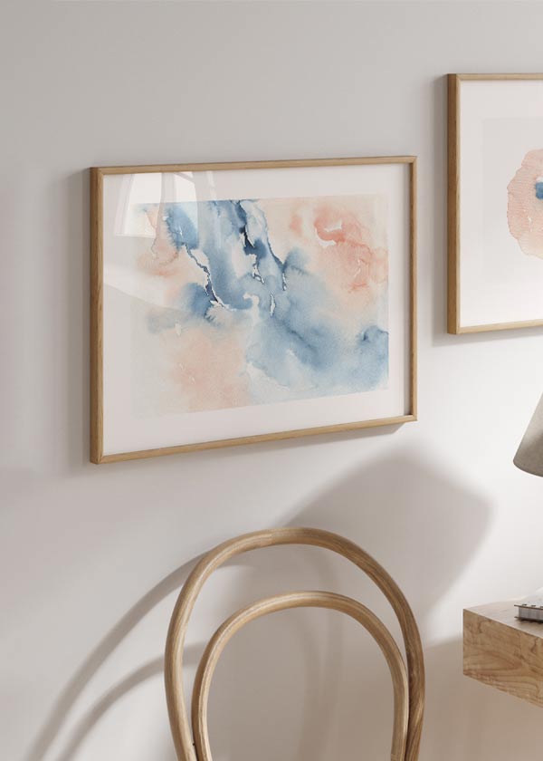 Quadro horizontal emoldurado com formas abstratas fluidas em azul acinzentado, branco e rosa poeirento, composição leve sobre fundo claro, estilo abstrato sereno e etéreo. Disponível em kudeko.com