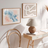 Cuadro horizontal con paisaje abstracto en tonos azul empolvado, blanco y rosa melocotón, de composición suave y estilo abstracto. Disponible en kudeko.com