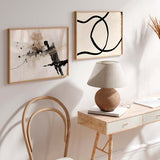 Horizontales Wandbild mit verflochtenen schwarzen Kurvenlinien auf hellem Beigeton, abstrakter Komposition mit klarem Kontrast und minimalistischem Stil. Erhältlich auf kudeko.com