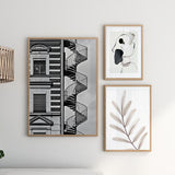 Wandbild mit urbaner Fassade in Schwarzweiß, außenliegender Wendeltreppe, klassischen Fenstern, markanten Architekturlinien und einzelner Figur im fotografischen, zeitgenössischen Stil. Erhältlich auf kudeko.com