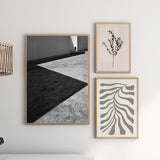 Quadro de cena arquitetónica a preto e branco com sombras diagonais, chão de betão texturado, figura humana distante e estilo fotográfico contemporâneo. Disponível em kudeko.com