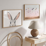 Cuadro horizontal de conejo gris claro asomándose, con orejas largas rosadas, ojos oscuros brillantes, fondo blanco limpio y estilo animales. Disponible en kudeko.com