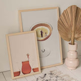 Gerahmtes Wandbild mit drei Gläsern voller rosafarbener Flüssigkeit, beigem Hintergrund, kleiner weiblicher Figur, cremefarbenen und terrakottafarbenen Tönen, surrealem minimalistischem Stil. Erhältlich auf kudeko.com