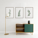 Tableau encadré avec branche stylisée de feuilles allongées vert sauge et vert grisé sur fond blanc, composition épurée au style minimaliste et élégant. Disponible sur kudeko.com