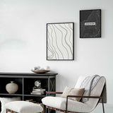 Tableau avec lignes topographiques noires ondulées sur fond blanc, composition épurée, style minimaliste et graphisme contemporain pour décoration murale. Disponible sur kudeko.com