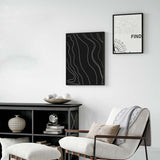 Gerahmtes Wandbild mit weißen, geschwungenen topografischen Linien auf schwarzem Hintergrund, abstrakte Komposition mit klarem Kontrast und minimalistischem Stil. Erhältlich auf kudeko.com