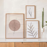Conjunto de tres cuadros con composición botánica de hojas delicadas, líneas negras finas, círculo rosa empolvado, beige suave y fondo claro, de estilo minimalista. Disponible en kudeko.com