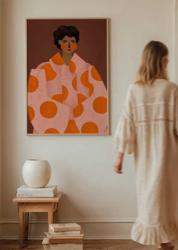 Cuadro ilustrado colorido con retrato femenino y abrigo rosado con círculos naranjas, obra de Bea Muller, kudeko.com
