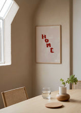 Cuadro con la palabra HOME en letras burdeos sobre fondo beige, kudeko.com
