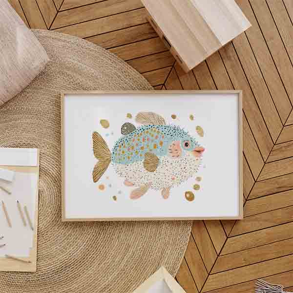 Horizontales Wandbild mit kindlichem Kugelfisch in Hellblau, Weiß, Gold und sanftem Rosa, umgeben von kleinen maritimen Formen auf hellem Hintergrund, im dekorativen Illustrationsstil für Kinderzimmer. Erhältlich auf kudeko.com