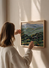 Tableau carré avec collines vertes ondulées, montagnes bleu gris au fond, végétation sombre au premier plan et style nature et paysage équilibré. Disponible sur kudeko.com