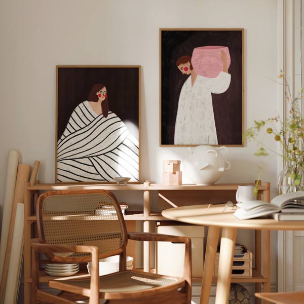 Set aus zwei Wandbildern mit stilisierten Frauen, weißer Decke mit schwarzen Streifen, rosa Korb, dunkelbraunem Hintergrund, roten Details und illustrativem Stil. Erhältlich auf kudeko.com