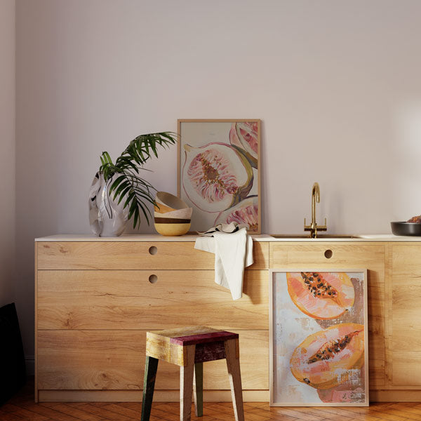 Conjunto de dois quadros com figo de polpa rosada e papaia laranja cortada, sementes escuras, fundos bege claro texturados e estilo de ilustração botânica contemporânea. Disponível em kudeko.com
