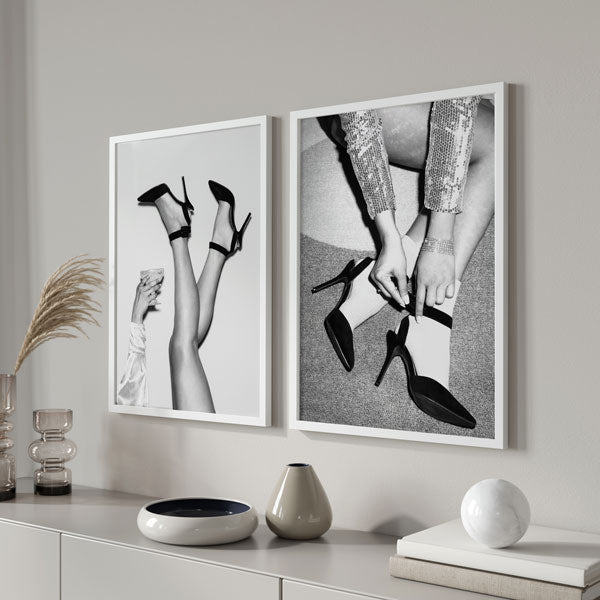 Set aus zwei Wandbildern mit Schwarz-Weiß-Fotografien von Frauenbeinen, schwarzen High Heels, Händen beim Anlegen von Armbändern und einem Cocktailglas im modeinspirierten Stil. Erhältlich auf kudeko.com