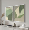 Ensemble de deux tableaux avec formes géométriques organiques superposées en vert sauge, vert mousse, beige et gris pierre, dans un style géométrique équilibré et doux. Disponible sur kudeko.com