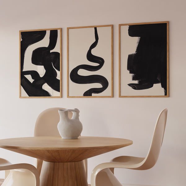 Conjunto de tres cuadros abstractos y minimalistas con formas en negro sobre un fondo ligeramente beige