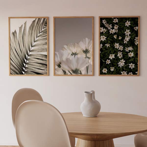 Set aus drei Wandbildern mit beigem Palmblatt, zarten weißen Blüten, dunkelgrünem Blattwerk und botanischer Gestaltung im nordischen Stil in neutralen Farben. Erhältlich auf kudeko.com