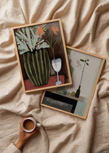 Tableau de nature morte minimaliste avec bouteilles élancées, verre transparent, branche aux feuilles sombres, petits fruits rouges et tons vert sauge, beige, noir et gris, dans un style épuré et équilibré. Disponible sur kudeko.com