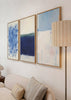 Conjunto de três quadros com composição abstrata em azul-marinho, azul-claro, branco sujo e bege suave, num estilo contemporâneo e equilibrado para decoração de parede. Disponível em kudeko.com