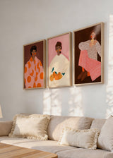 Set aus drei gerahmten Wandbildern mit Frauenporträts, ruhigen Gesichtszügen, gemusterter Kleidung, Orangen, rosa und braunen Hintergründen im zeitgenössischen Illustrationsstil. Erhältlich auf kudeko.com