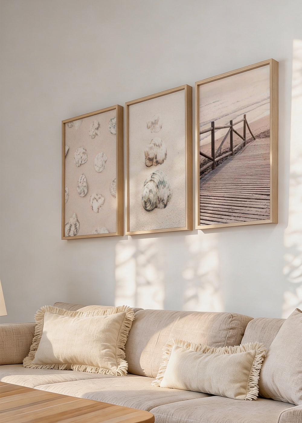 Set aus drei Wandbildern mit Muscheln am Strand, Holzsteg zum Meer, hellem Sand, Altrosa, Weiß, sanftem Beige und fotografischem Küstenstil. Erhältlich auf kudeko.com