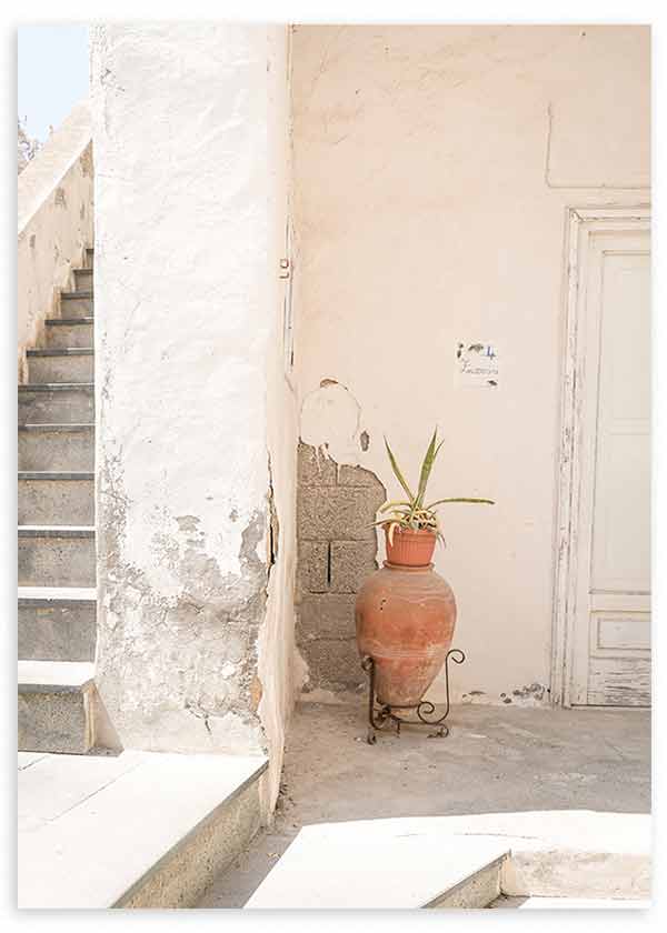 Cuadro de rincón mediterráneo con escalera de piedra, pared blanca envejecida, puerta clara, vasija de terracota y planta verde, de estilo fotográfico. Disponible en kudeko.com