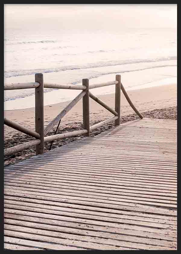 Cuadro de una pasarela de madera frente al mar con barandilla rústica, arena clara, olas suaves y tonos beige, crema y gris en estilo fotográfico. Disponible en kudeko.com